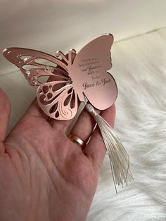 a hand holding a rose gold butterfly brooch