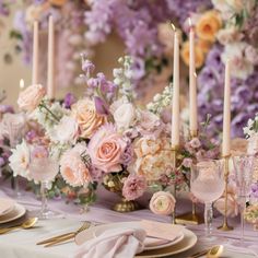 the table is set with pink and white flowers, gold place settings, and candles