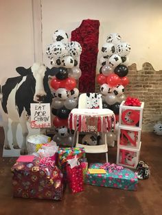 balloons, presents and other items are on the floor in front of a cow statue