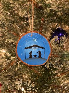 a christmas ornament hanging from a tree with a nativity scene on it