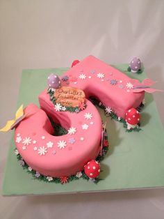 a cake shaped like the number 50 with flowers and ladybugs around it on a green plate