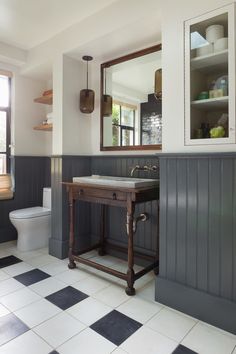 a bathroom with black and white tile flooring and gray walls, along with a wooden vanity