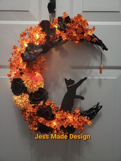 a halloween wreath with black cats and orange flowers on the front door is lit up