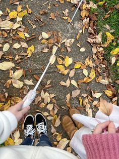 two people sitting on the ground holding umbrellas in front of some leaves and grass