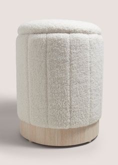 a white stool with wooden legs and a round cover on the top, in front of a gray background