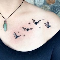 a woman's chest with some bats and stars on it, as well as a green stone pendant