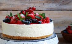 a cheesecake with berries on top is sitting on a cake platter, ready to be eaten