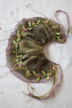 a piece of cloth with flowers and leaves on it sitting on a white tablecloth