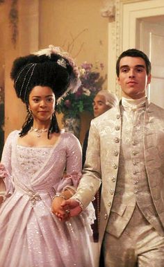 a man and woman dressed in wedding attire standing next to each other, holding hands