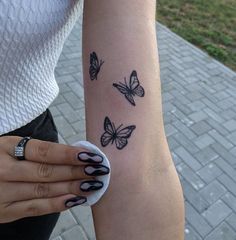 a woman's arm with three butterflies on the left side of her wrist and one butterfly on the right