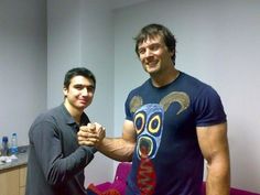 two men standing next to each other in front of a mirror with their hands together