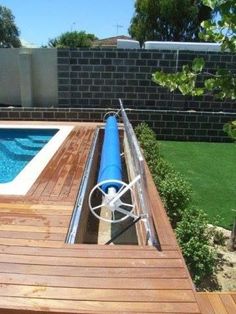 an above ground swimming pool in the middle of a backyard with a wooden deck and fence around it