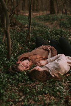 a woman is laying on the ground in the woods