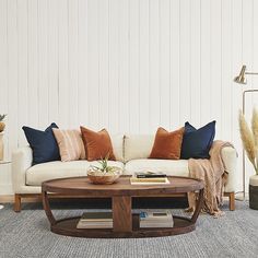 a living room filled with furniture and pillows on top of a rug next to a coffee table