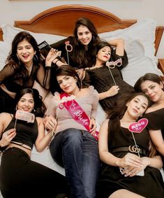 a group of young women laying on top of a bed holding lollipops