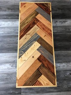 a wooden table with different colored wood planks on the top and bottom side, along with a gray floor