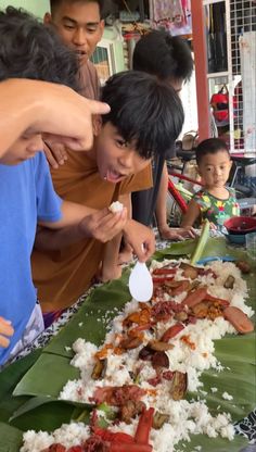 a group of people standing around a table with food on it