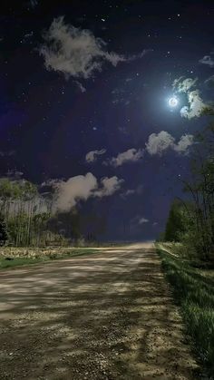 the night sky is full of stars and clouds, as seen from an empty dirt road