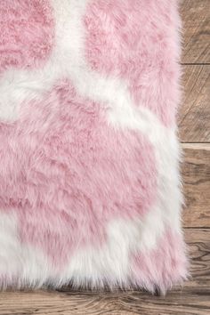 a pink and white fur pillow on top of a wooden floor