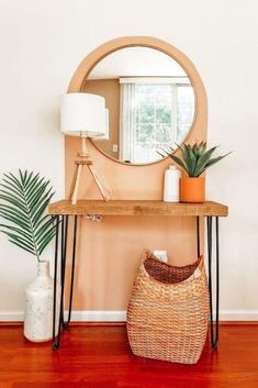 a table with a mirror, plant and basket on it in front of a window