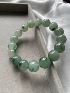 Item Code: JBD226001  Burmese Grade A Jadeite Jade Carved out from a single stone, this piece of jadeite bead bracelet is one of the uncommon ones in the market. Great translucency due to it being the icy type jadeite. One notable feature is the fine texture of each of the beads. The color of this bead bracelet varies according to the lighting of the surrounding but its true color which can be seen under natural lighting as taken in the last picture is misty green. Each of the beads has green floating flowers which is an added value to the piece. All our photos were taken under natural light settings to showcase the true essence and colours of the pieces. We condemn the uses of any photo editing softwares to alter the colours of the pictures taken. We try to capture the true colours of the Elegant Green Agate Crystal Bracelet, Elegant Jade Bracelets With Round Beads, Green Aventurine Gemstone Beaded Bracelets, Elegant Jade Crystal Bracelet With Round Beads, Jade 8mm Beads Round Jewelry, 8mm Round Jade Bead Jewelry, Jade Jewelry With 8mm Round Beads, Green Polished Beaded Bracelets, Elegant Jade Bracelets With Polished Beads