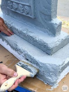 a person is using a brush to paint the base of a building with cement blocks