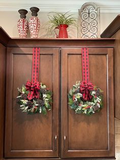 two christmas wreaths on top of a cabinet