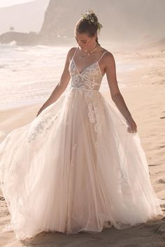 a woman in a wedding dress walking on the beach