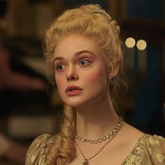 a woman with blonde hair and blue eyes wearing a gold dress in a scene from game of thrones