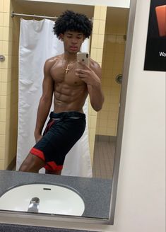 a shirtless man taking a selfie in a bathroom mirror with his cell phone