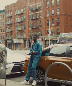 a man standing next to a parking meter on the side of a road near parked cars