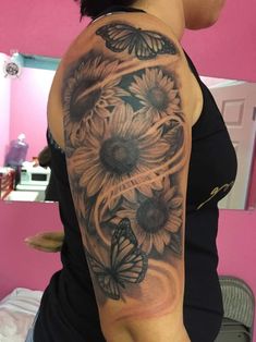 a woman's arm with sunflowers and butterflies tattoo on her left arm