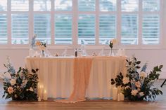 the table is set up with flowers and candles for an elegant wedding breakfast or reception