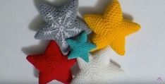 five crocheted stars are arranged on a white surface, one is red, one is blue and the other is yellow