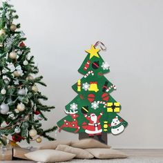 a small christmas tree sitting next to a pile of pillows on top of a wooden floor