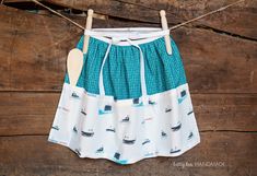 a skirt hanging from a clothes line with boats printed on it and a wooden hanger