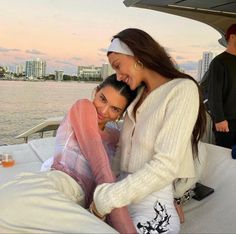 two women are sitting on the back of a boat and posing for a photo together