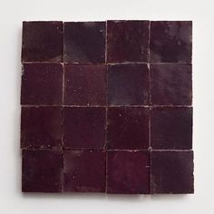 a square piece of red tile sitting on top of a white wall