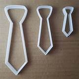 three pieces of plastic that are shaped like ties on a brown surface, one is white and the other is black