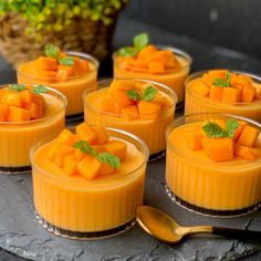 small desserts are arranged in glass dishes on a tray with gold spoons next to them