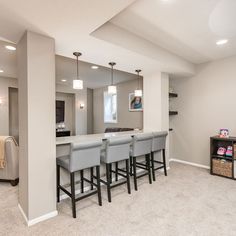 a kitchen and living room with bar stools in the middle of the room that is empty