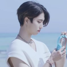 a woman standing on the beach holding a water bottle