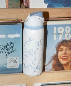 a white water bottle sitting on top of a wooden shelf next to books and magazines