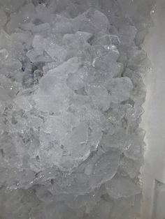 an ice bucket filled with lots of ice next to a white box full of water