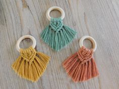 three tasseled wooden key chains sitting on top of a wooden table