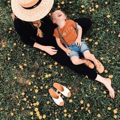 two people laying in the grass with hats on their heads and one person holding a child