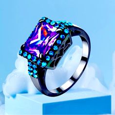 Black Gold Plated Sterling Silver Women’s Ring Square Cut Purple And Blue Zircon Ring With Turquoise Accent Crystal A Black Gold Plated Sterling Silver .925 Ring With A Purple Stone As The Centerpiece And Accented With Turquoise Crystals In A Raised Square Cut Setting Is An Elegant Option. Lab-Created Amethysts Offer The Rich Purple Hue Of Natural Amethysts. The Combination Of Rich Purple Amethysts And Vibrant Turquoise Creates An Eye-Catching And Unique Piece Of Jewelry. This Ring Is Perfect Fo Trendy Blue Ring For Parties, Trendy Blue Party Ring, Sketch Bases, Blue Zircon Ring, Turquoise Crystals, Solitaire Bracelet, Ring Square, Turquoise Accents, Turquoise Crystal