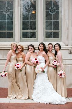 a group of women standing next to each other in front of a building holding bouquets