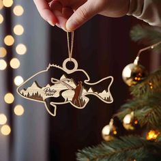 someone is holding a christmas ornament with a fish in the shape of a fish