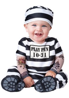 a baby sitting on the ground wearing a jail outfit